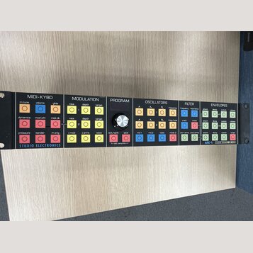 Černý rackový syntetizátor s bílým panelem a barevnými ovládacími tlačítky. Na panelu jsou nápisy STUDIO ELECTRONICS, ATC-1 a TONE CHAMELEON. Ovládac…