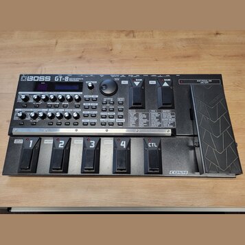 Černý kytarový efektový procesor s nápisem BOSS GT-8 GUITAR EFFECTS PROCESSOR. Zařízení má ovládací panel s knoflíky, tlačítky a displejem, v dolní č…
