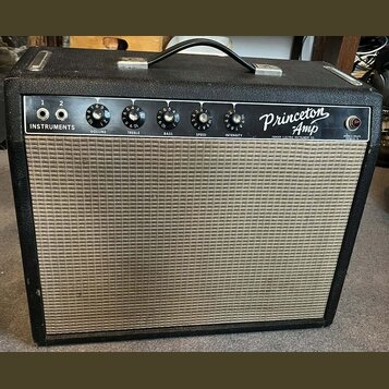Kytarový zesilovač v černém krytu s béžovou textilní mřížkou. Na ovládacím panelu je nápis Princeton Amp a Fender Electric Instrument Co., dále označ…