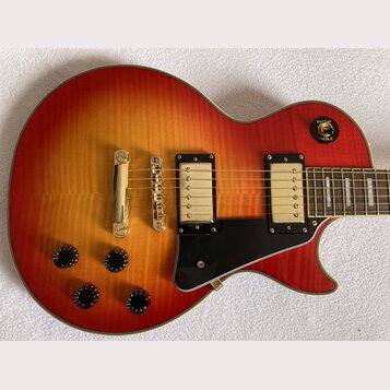 Elektrická kytara s tělem v červeno-žlutém sunburst provedení a černým pickguardem. Nástroj má dva humbuckery s krémovými kryty a čtyři černé ovládac…