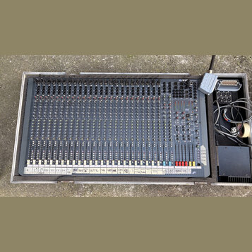 Široký míchací pult v šedé barvě umístěný v transportním kufru. V pravém horním rohu je viditelné logo s nápisem Soundcraft. Spodní hranu pultu doplň…