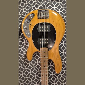 Kytara s přírodním dřevěným povrchem a černým kruhovým pickguardem. Na těle jsou dva černé humbuckery, chromovaný most a ovládací panel s dvěma knofl…