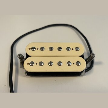 Kytarový humbucker s krémovými plastovými kryty. Snímač má dvě řady šesti poladitelných šroubů. Na povrchu nejsou viditelné žádné značky ani nápisy.…