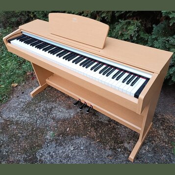 Digitální piano v dřevěné barvě s klasickým provedením. Nástroj má bílé a černé klávesy, tři sustain pedály a nápis "KORG" na horním víku. Povrch nás…