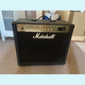 Černý kytarový kombo zesilovač s látkovou mřížkou. Na přední straně je bílé logo Marshall a na ovládacím panelu nápis MG 100W. Panel obsahuje řadu ot…