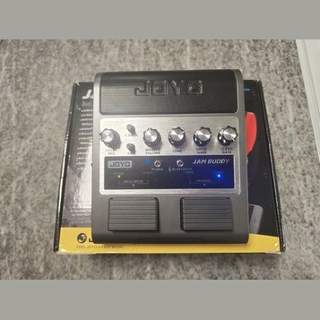 Kytarový zesilovač značky JOYO, model JAM BUDDY, v černé barvě. Přední panel obsahuje ovládací knoflíky DELAY MIX, TIME, MASTER VOLUME, TONE, DRIVE G…