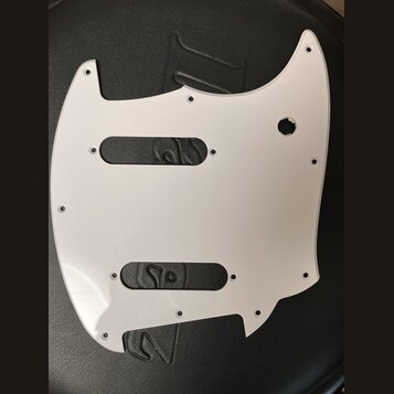 Bílá plastová pickguard pro elektrickou kytaru s dvěma obdélníkovými výřezy na snímače a kulatým otvorem pro ovládací prvek. Povrch je hladký, bez vi…