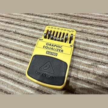 Žlutý kytarový pedál s nápisem GRAPHIC EQUALIZER a označením modelu EQ700. Na horní straně se nachází sedm posuvníků s popisy frekvencí 100, 200, 400…