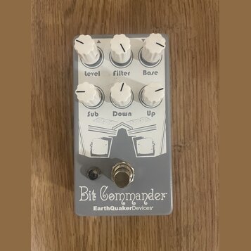 Šedý kytarový efekt s bílými ovládacími knoflíky. Na spodní části je nápis Bit Commander a pod ním značka EarthQuakerDevices. Knoflíky jsou popsány j…