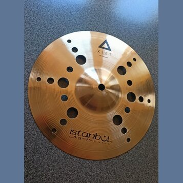 Zlatavý kovový činel s otvory různých velikostí v celém těle. Na povrchu je nápis XIST 10" ION Splash s trojúhelníkovým logem a v dolní části nápis i…