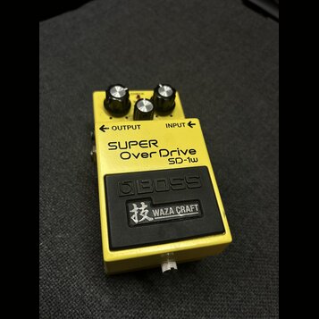 Žlutý kytarový efekt pedál s černým spodním panelem. Na horní části je nápis SUPER Over Drive SD-1w a logo BOSS, pod kterým je štítek s nápisem 技 WAZ…