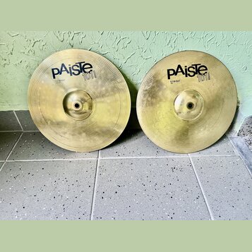 Dvě mosazné činely typu hi-hat v zlatavé barvě s koncentrickým žilováním. Oba mají černý nápis pAiste 101 BRASS a pod ním označení 12" HI-HAT. Povrch…
