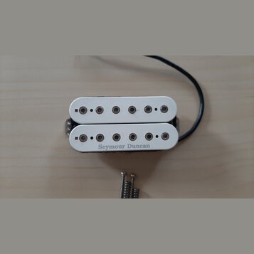 Bílý humbucker s dvěma řadami šesti polových magnetů. Na spodním rámečku je černý nápis Seymour Duncan. K snímači vede černý kabel a vedle něj jsou p…