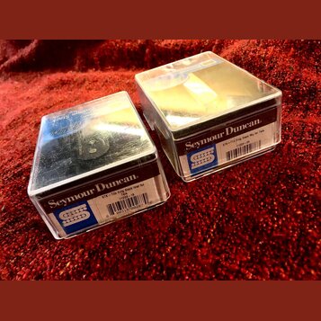 Dvě průhledná plastová krabičky s hudebním příslušením položené na červeném textilu. Na krabičce vlevo je nápis Seymour Duncan, STK-T3b Vntg Stack le…
