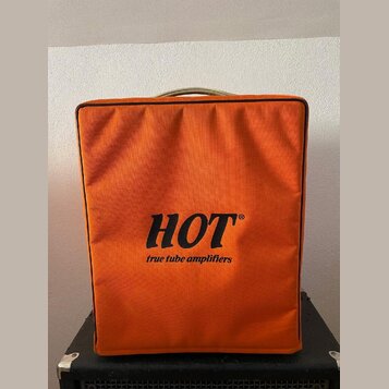 Oranžový textilní kryt na hudební zesilovač. Uprostřed je černý nápis HOT® a pod ním menší text true tube amplifiers. Kryt vykazuje mírné opotřebení…