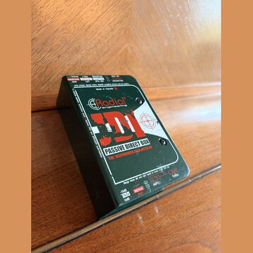 Tmavě zelená pasivní DI box s nápisem Radial engineering a modelem JDI. Na horní straně je text PASSIVE DIRECT BOX, TRNSFORMER ISOLATED DI a Made in…