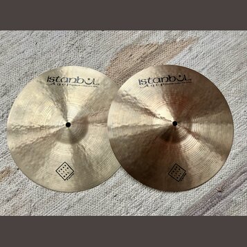 Dvě mosazné činely s viditelným rýhováním povrchu. Oba mají nápisy istanbul Agop Handmade cymbals from Turkey a v dolní části logo TRADITIONAL. Povrc…