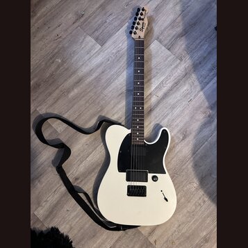 Bílá elektrická kytara typu Telecaster s černým pickguardem a černými snímači. Na hlavě hnedu je vidět nápis "Squier" a vedle něj model "BULLET". Kyt…