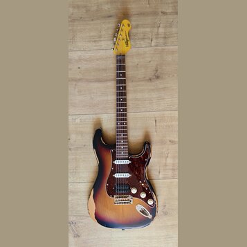 Elektrická kytara s tłem v barvě sunburst a hnědým pickguardem. Na hlavě je viditelné logo "Vanguard" a nápis "ICON Series". Tělo kytary vykazuje výr…