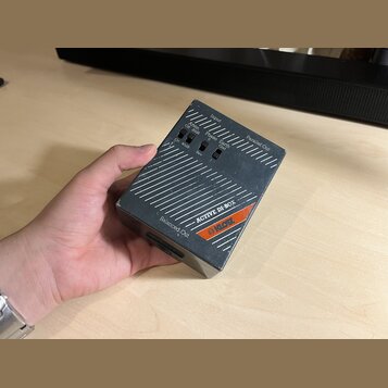 Šedý kovový box s nápisem ACTIVE DI-BOX a oranžovým logem klotz. Na horní straně jsou přepínače s popisky Atten. Off 20dB / On 40dB, Phase 0 / Rev a…