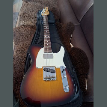 Elektrická kytara s tělem v barvě sunburst a bílým pickguardem, položená na černém obalu. Na hlavě hředu je viditelné logo "Ltd". Nástroj vykazuje zn…