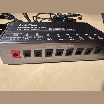 Černý napájecí zdroj s kovovým povrchem a nápisem Harley Benton POWERPLANT ISO-2 PRO ISOLATED OUTPUT POWER SUPPLY. Zařízení má jeden červený vstup PO…