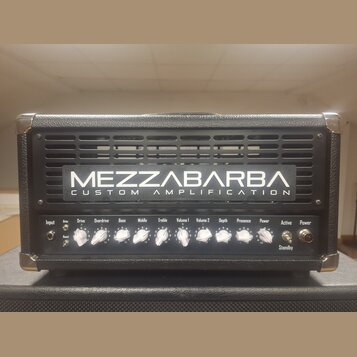 Černý kytarový zesilovač s kovovými rohy. Na přední mřížce je nápis MEZZABARBA CUSTOM AMPLIFICATION. Ovládací panel obsahuje knoflíky s popisky Input…