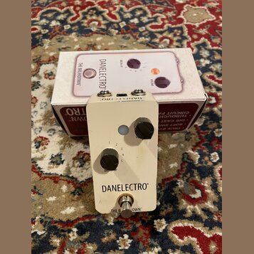 Bílý kytarový efekt pedál značky DANELECTRO s nápisem THE BREAKDOWN™. Na horní straně jsou dva černé otočné knoflíky s popisky VOLUME a BREAKUP (ozna…