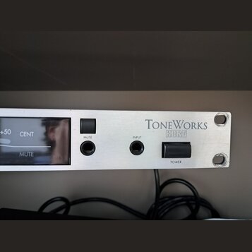 Stříbrný rackový přístroj s nápisy TONEWORKS a KORG. Na předním panelu jsou umístěny dva přepínače s popisky MUTE a POWER, vstupní konektor INPUT a d…