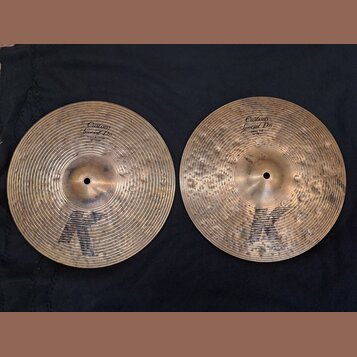 Dvě mosazné činely s výrazným kladivováním a černým logem K ve spodní části. Levý činele má nápisy Custom Special Dry a HIHAT BOTTOM 14" 70 cm. Pravý…