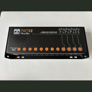 Černý napájecí adaptér pro pedály s nápisem Palmer PWT12 Power Bar. Zařízení obsahuje dvanáct očíslovaných výstupů a vstup označený jako Power Input…