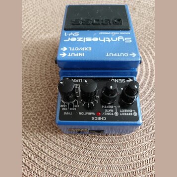 Modrý kytarový efekt s černým pedálem, na kterém je vyražen nápis BOSS. Na horní straně jsou bílé nápisy Synthesizer SY-1, SOUND HOLD (PRESS), INPUT,…