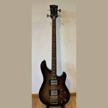 Tmavně hnědá elektrická basová kytara s tmavým hnedým hnedým dřevěným hmatníkem. Na hlavě nástroje je nápis Superstar. Kytara má dva humbuckery, tři…