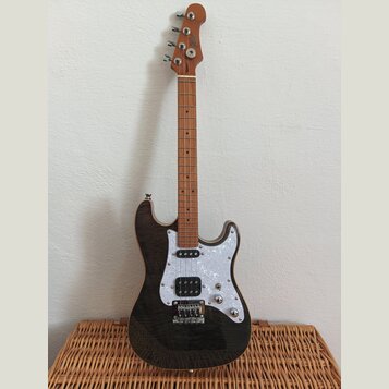 Elektrická kytara s tmavým, pravděpodobně černým lakem s viditelnou strukturou dřeva. Má bílý perleťový pickguard, jeden humbucker u mostu a dva sním…