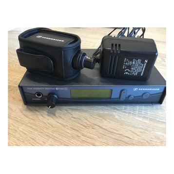 Černý přijímač s nápisem TRUE DIVERSITY RECEIVER GW500 G2 a logem SENNHEISER. Na přístroji je umístěn černý adaptér s nápisem SENNHEISER MODEL G 2347…