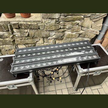 Tři černé lineární LED páse s kulatými světelnými zdroji, umístěné na dvou transportních kufrech. Zařízení jsou propojena černými kabely s žlutými sp…