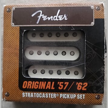 Sada tří bílých snímačů pro kytaru v originálním kartonovém obalu. Na horní části je logo Fender a ve spodní části nápisy ORIGINAL '57 / '62 STRATOCA…