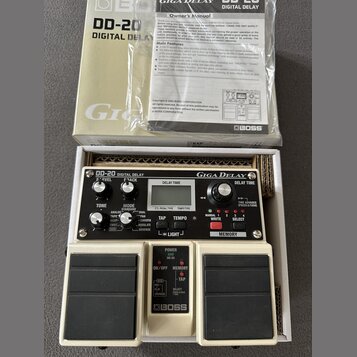 Bílá kytarový efekt Boss DD-20 Giga Delay v originálním obalu s přiloženým manuálem. Na zařízení jsou viditelné nápisy DD-20 DIGITAL DELAY, Giga Dela…
