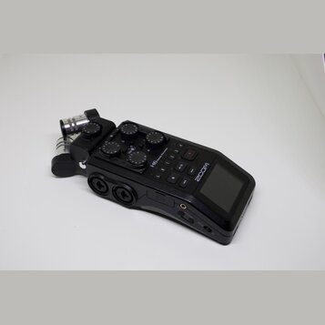 Černý digitální nahrávač značky ZOOM s modelem H6 handy Recorder. Zařízení má integrovaný displej, ovládací tlačítka a několik regulačních knoflíků.…