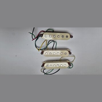 Tři krémově bílé snímače pro elektrickou kytaru s šesti kovovými póly. Každý snímač má v levé části nápis NPS a je vybaven připojovacími vodiči v růz…