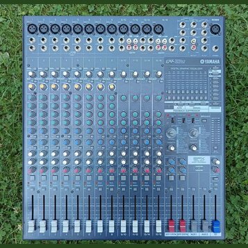 Šedý mixovací pult značky YAMAHA s označením modelu EMX5016cF. Zařízení obsahuje více vstupních kanálů s posuvníky, řadu otočných knoflíků v různých…