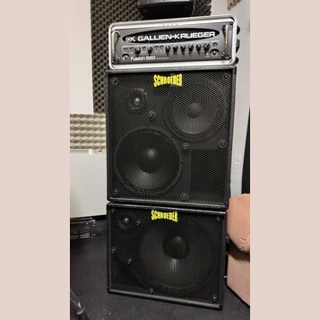Sada basového zesilovače a dvou reproduktorových skříní. Nahoře je rackový zesilovač s nápisy GALLIEN-KRUEGER a Fusion 550. Pod ním jsou dvě černé re…
