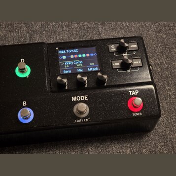Černý kytarový efekt s displejem a ovládacími prvky. Na displeji je vidět text „02A Torn SC“ a „Kinky Comp“ s parametry Sens 5.0, Mix 100% a Attack 0…