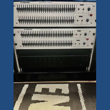 Dvě identické rackové jednotky s nápisem KLARK-TEKNIK DN360 GRAPHIC EQUALISER. Každý přístroj má dvě řady posuvníků s označením kmitočtů od 25 do 20k…