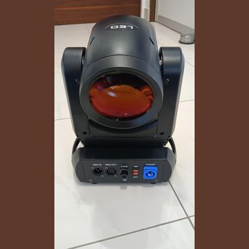 Černý LED reflektor s červeným filtrem na čočce. Na horní části je nápis LED. Zadní panel obsahuje konektory s popisky DMX IN, DMX OUT, FUSE a POWER,…