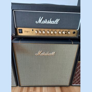 Kytarový zesilovač a reproduktorové boxy značky Marshall. Horní kombo má zlatý ovládací panel s nápisem Haze 100 a sekcemi Effects, EQ a Overdrive. S…