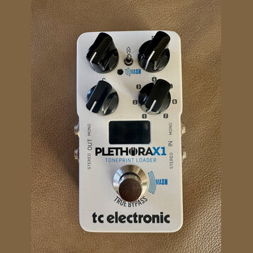 Bílý kytarový efekt s nápisy PLETHORAX1 a TONEPRINT LOADER. Na spodní části je logo tc electronic a nápis TRUE BYPASS. Zařízení má čtyři černé otočné…