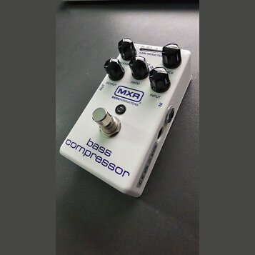Bílý efekt pedál s nápisy MXR BASS INNOVATIONS a bass compressor. Na horní straně jsou čtyři černé otočné ovířky s popisky RELEASE, RATIO, GAIN REDUC…