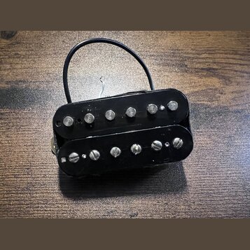 Černý humbucker s dvěma řadami šesti polkových snímačů. Nástroj nemá žádné viditelné značky ani nápisy. Z těla vychází černý kabel s bílým vodičem.