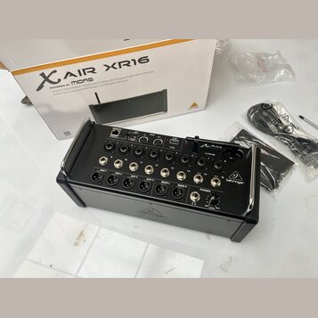 Černý digitální mixér s nápisy XAIR XR16 a behringer. Zařízení má řadu vstupních konektorů, včetně AUX 1 až 4 a MAIN L/R. Vedle mixéru je umístěna je…
